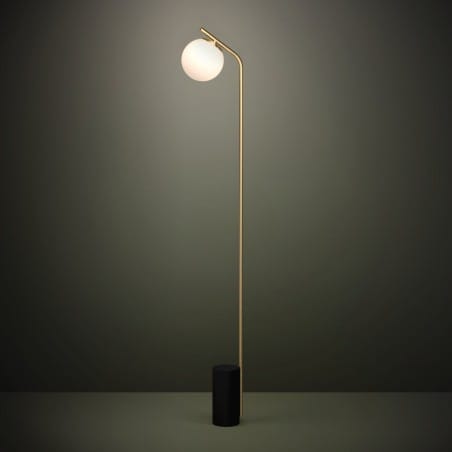 Nowoczesna minimalistyczna lampa stojąca przy kanapie Betulia czarna podstawa mosiężne ramię klosz szklana kula
